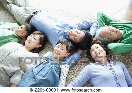 Stock Image - Family lying down on carpet. Fotosearch