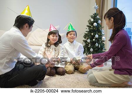 Family wearing party hats with birthday present View Large Photo Image Picture - Family wearing party hats with birthday present. Fotosearch