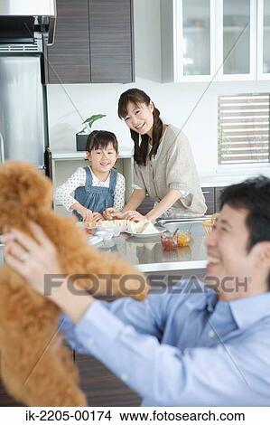 Father holding dog with family in background View Large Photo Image Picture - Father holding dog with family in background. Fotosearch