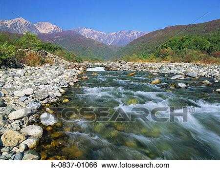 Stock Photograph - Fresh water flowing rapidly with mountains in background. Fotosearch