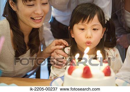 Stock Photo - Girl blowing candles with her mother. Fotosearch