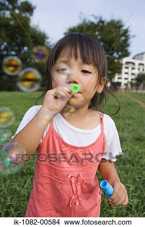 Picture - Girl blowing soap bubbles in park. Fotosearch