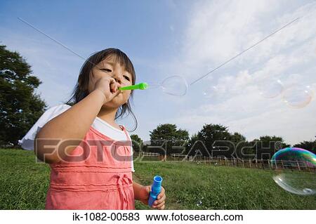 Girl blowing soap bubbles in park View Large Photo Image Stock Image - Girl blowing soap bubbles in park. Fotosearch