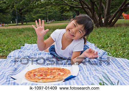 Girl eating pizza lying on a blanket View Large Photo Image Stock Photo - Girl eating pizza lying on a blanket. Fotosearch
