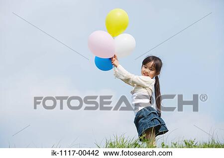 Girl holding colorful balloons against blue sky View Large Photo Image Stock Image - Girl holding colorful balloons against blue sky. Fotosearch