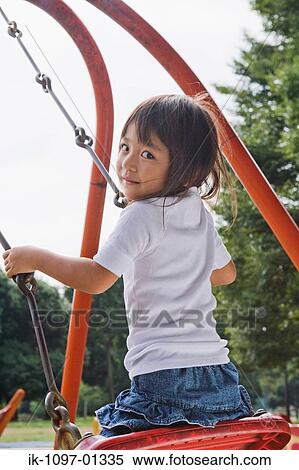 Girl in a park swinging on a playground swing View Large Photo Image Stock Photography - Girl in a park swinging on a playground swing. Fotosearch
