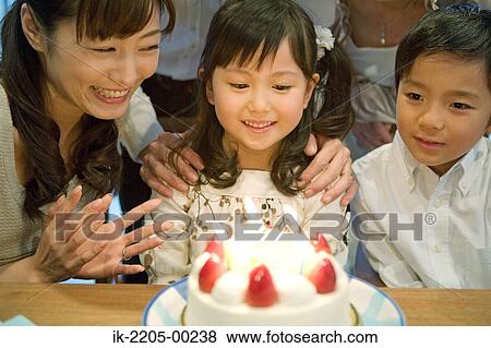 Girl looking her birthday cake with her family View Large Photo Image Stock Photo - Girl looking her birthday cake with her family. Fotosearch