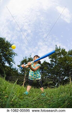 Stock Photography - Girl playing baseball in park. Fotosearch