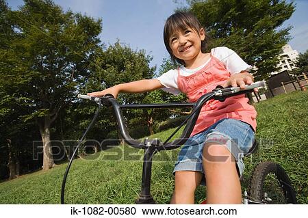Girl riding bicycle in park View Large Photo Image Stock Image - Girl riding bicycle in park. Fotosearch