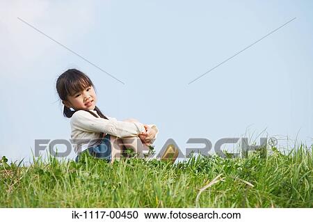 Stock Image - Girl sitting in park and looking at camera. Fotosearch