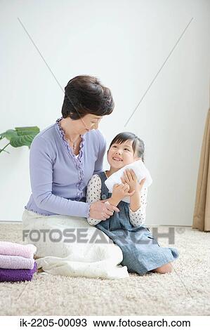 Stock Image - Girl with grandma folding clothes. Fotosearch