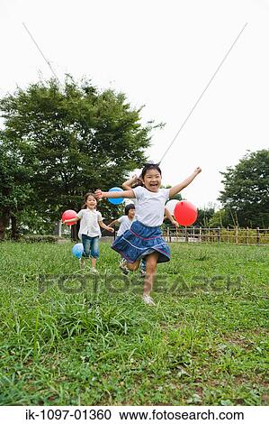 Girls playing with ballons in a park View Large Photo Image Stock Image - Girls playing with ballons in a park. Fotosearch