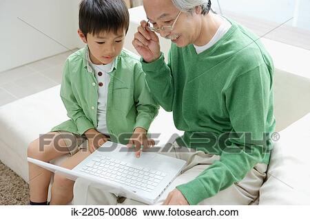 Stock Photograph - Grandson showing laptop to grandfather. Fotosearch
