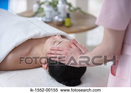Stock Photography - Hands of a person massaging forehead of a woman. Fotosearch