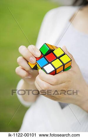 Stock Image - Hands of a woman with Rubik's cube. Fotosearch