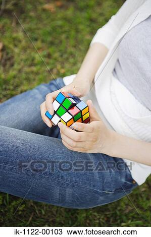 Stock Image - Hands of a woman with Rubik's cube. Fotosearch