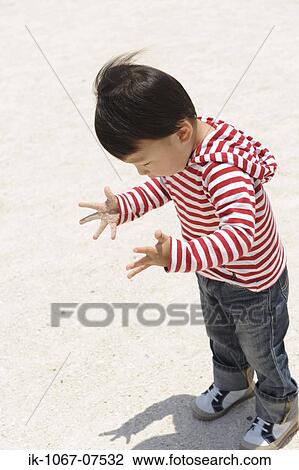 Stock Image - Japanese boy looking down for sand. Fotosearch