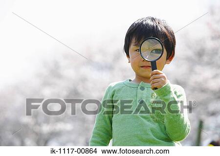 Picture - Japanese boy looking through magnifying glass. Fotosearch
