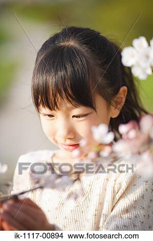 Picture - Japanese girl looking at flowers. Fotosearch