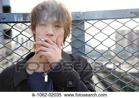 Stock Photography - Japanese man blowing smoke in the city. Fotosearch