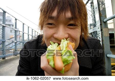 Stock Photo - Japanese man enjoying hot dog. Fotosearch