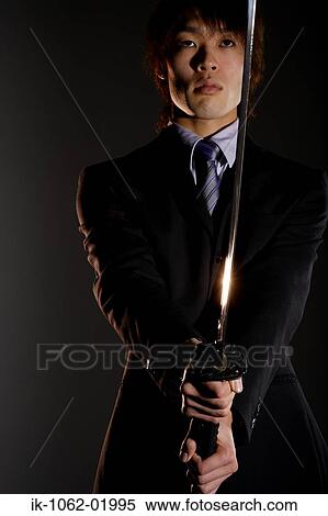 Stock Photography - Japanese man holding a sword in fighting stance in Studio. Fotosearch