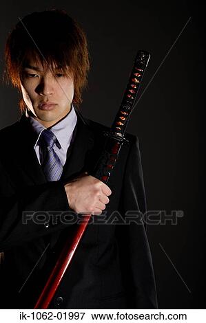 Stock Photo - Japanese man holding a sword with one hand over his heart. Fotosearch