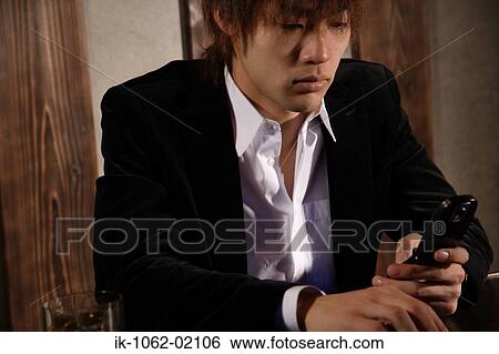 Stock Photograph - Japanese man holding cellphone with a cigarette at the same time. Fotosearch