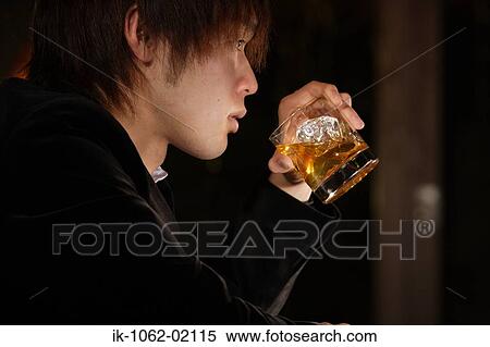 Stock Photography - Japanese man holding scotch-whiskey (side view) in bar. Fotosearch