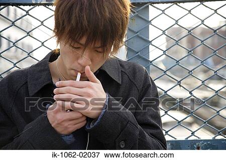 Japanese man lighting a cigarette outside in the city View Large Photo Image Stock Photo - Japanese man lighting a cigarette outside in the city. Fotosearch