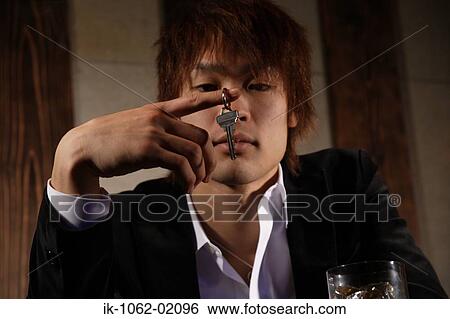 Stock Photograph - Japanese man looking at key with bored look. Fotosearch