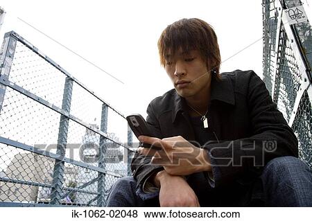 Japanese man playing with his cellphone View Large Photo Image Stock Photo - Japanese man playing with his cellphone. Fotosearch