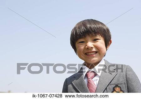 Stock Photo - Japanese schoolboy smiling against clear sky. Fotosearch