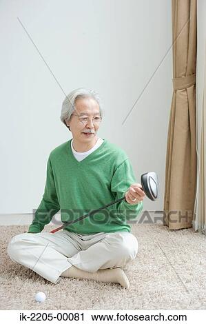 Stock Image - Japanese senior man holding putter. Fotosearch