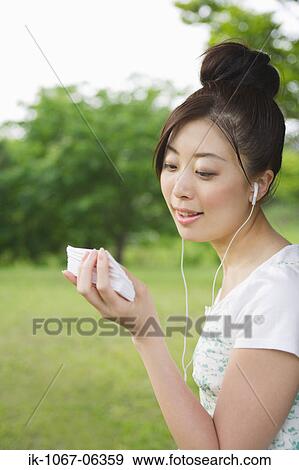 Stock Photo - Japanese woman listening music and holding cards. Fotosearch