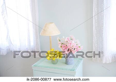 Stock Photo - Lamp and Vase of Flowers on Sideboard in Room. Fotosearch