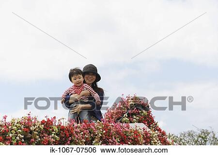 Mother holding baby on flowers decorated balcony against sky View Large Photo Image Stock Photograph - Mother holding baby on flowers decorated balcony against sky. Fotosearch