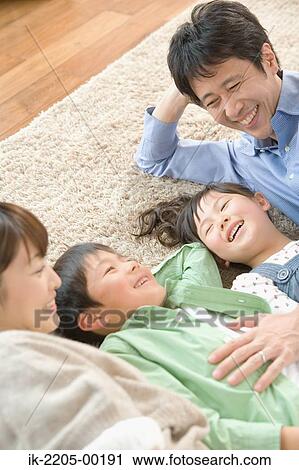 Stock Image - Parents with their children lying on carpet. Fotosearch