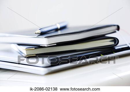 Stock Photo - Pen lying on stacked diaries. Fotosearch