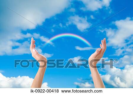 Stock Photo - Rainbow Over Human Hands against Cloudy Sky. Fotosearch