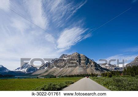 Stock Image - Road Approaching Snow –Covered Mountains. Fotosearch
