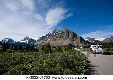 Stock Image - Road Approaching Snow –Covered Mountains. Fotosearch