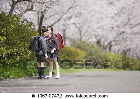 Stock Image - Schoolmate whispering on road. Fotosearch