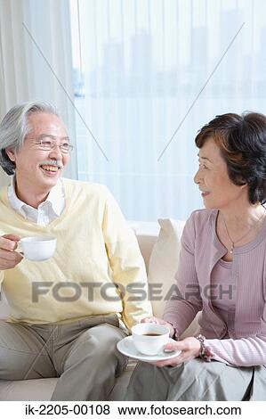 Senior couple having coffee on couch in living room View Large Photo Image Stock Photo - Senior couple having coffee on couch in living room. Fotosearch