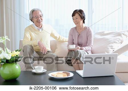 Senior couple having coffee on couch in living room View Large Photo Image Stock Photograph - Senior couple having coffee on couch in living room. Fotosearch