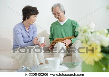Stock Photograph - Senior couple on couch with their dog. Fotosearch