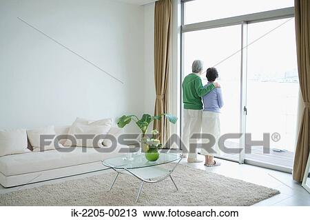 Stock Image - Senior couple standing in front door. Fotosearch