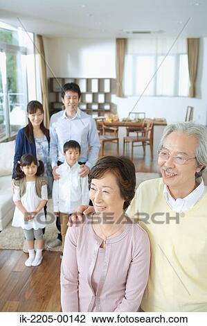 Stock Image - Senior couple standing together with his family in backgroud. Fotosearch