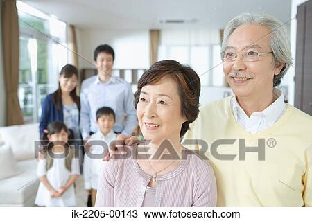 Stock Image - Senior couple standing together with his family in backgroud. Fotosearch