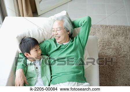 Picture - Senior man with grandson relaxing on couch. Fotosearch